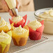 A person putting Rich's cream cheese icing on a cupcake.