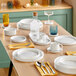 A table with white plates and Acopa Lore wine glasses on it.